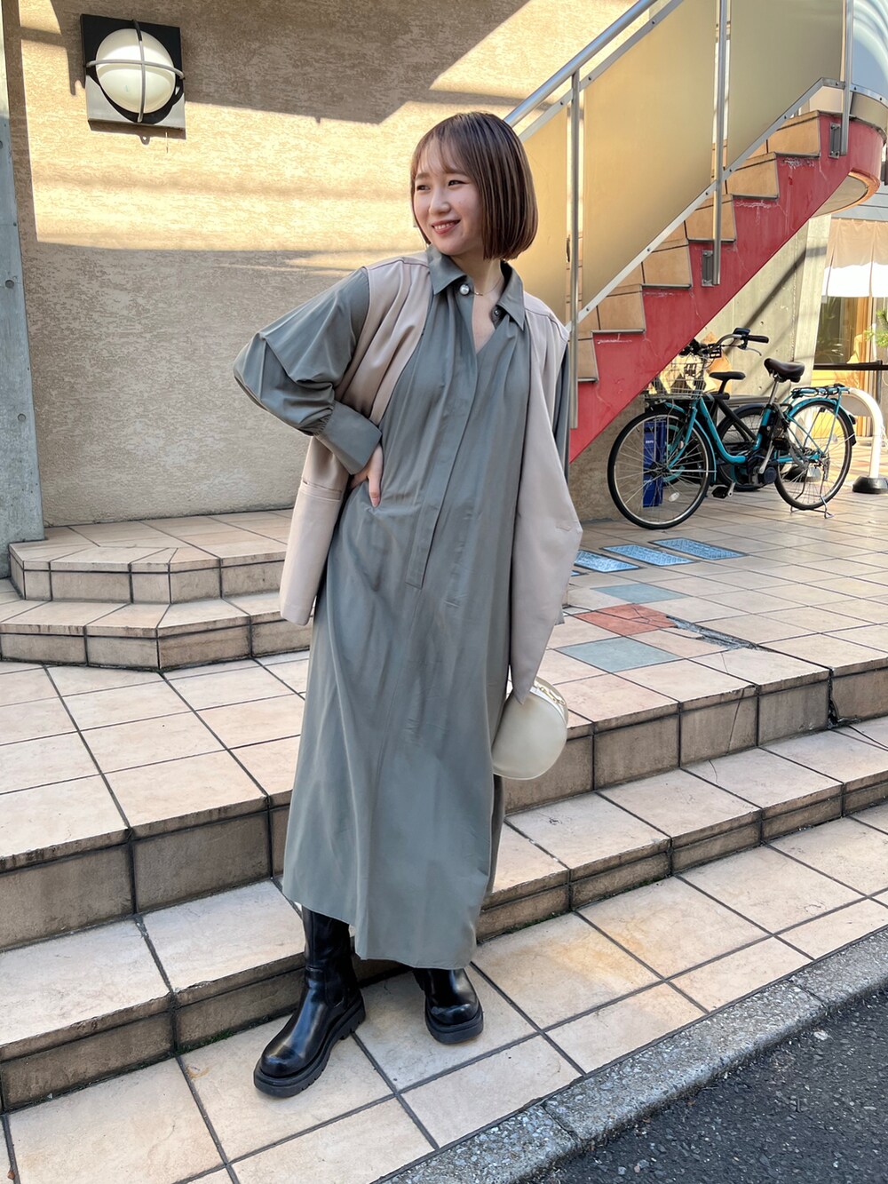 グリーン系のワンピース、ベージュ系のベスト、ホワイト系のハンドバッグを着用したレディースの冬コーディネートの2枚目の写真