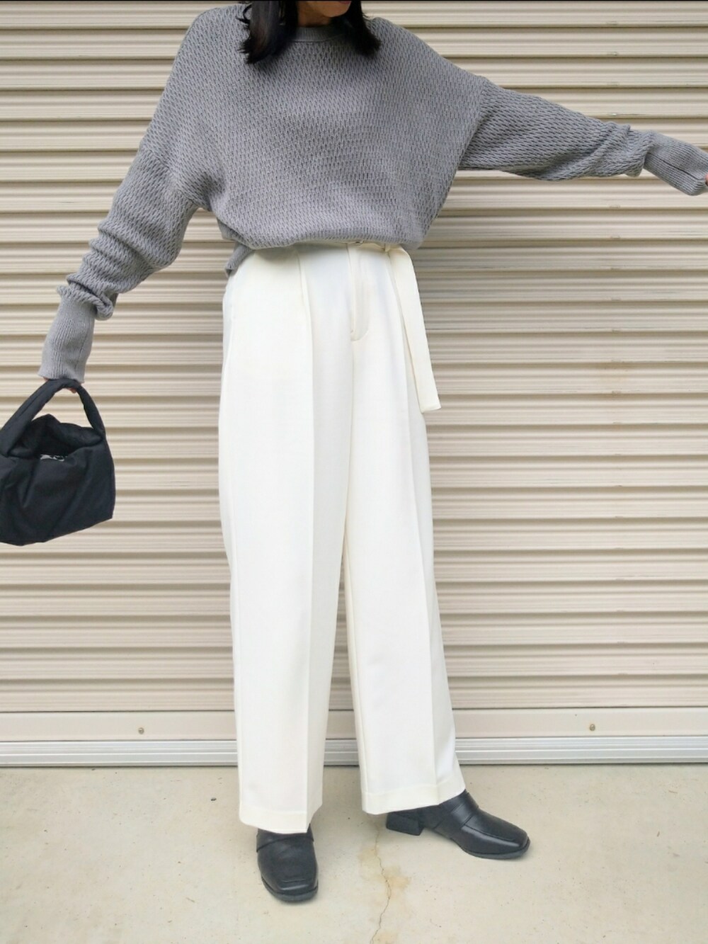 グレー系のニット/セーター、ホワイト系のその他パンツ、ブラック系のハンドバッグを着用したレディースの秋コーディネートの3枚目の写真