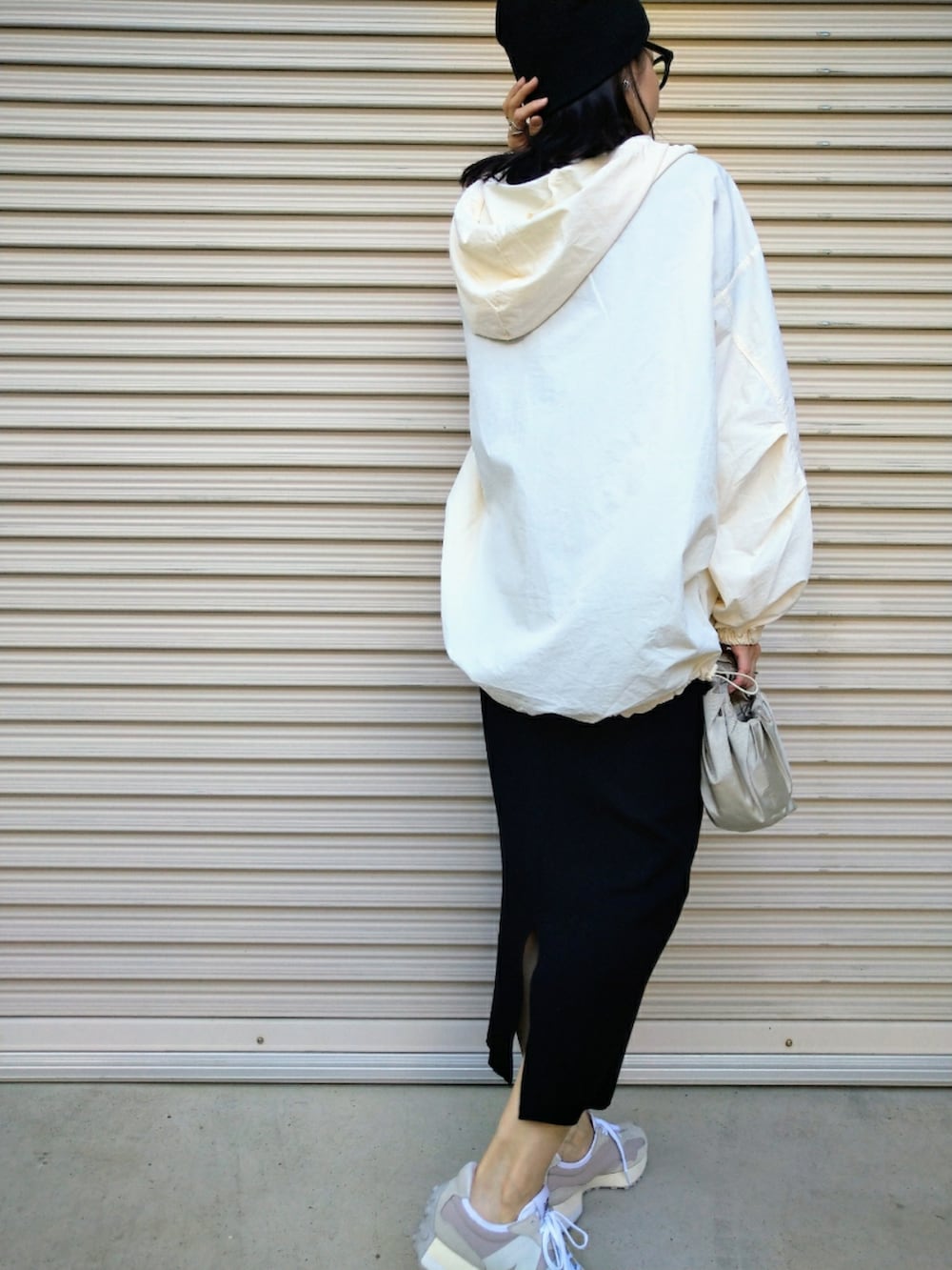 ブラック系のスカート、シルバー系のハンドバッグ、ベージュ系のスニーカーを着用したレディースの秋コーディネートの3枚目の写真