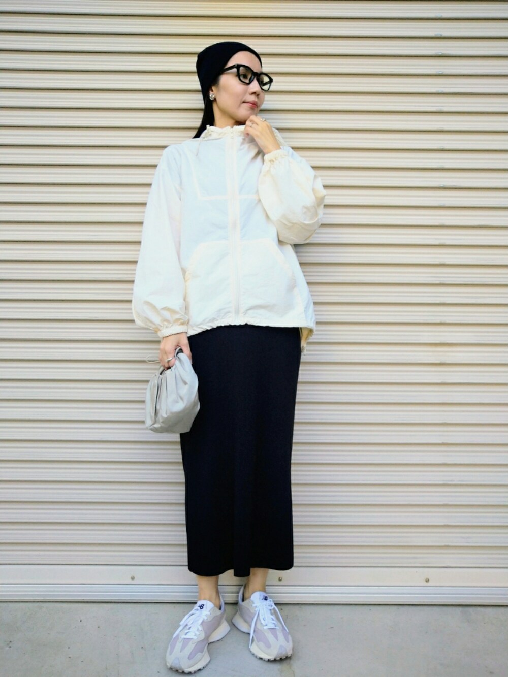 ブラック系のスカート、シルバー系のハンドバッグ、ベージュ系のスニーカーを着用したレディースの秋コーディネートの2枚目の写真