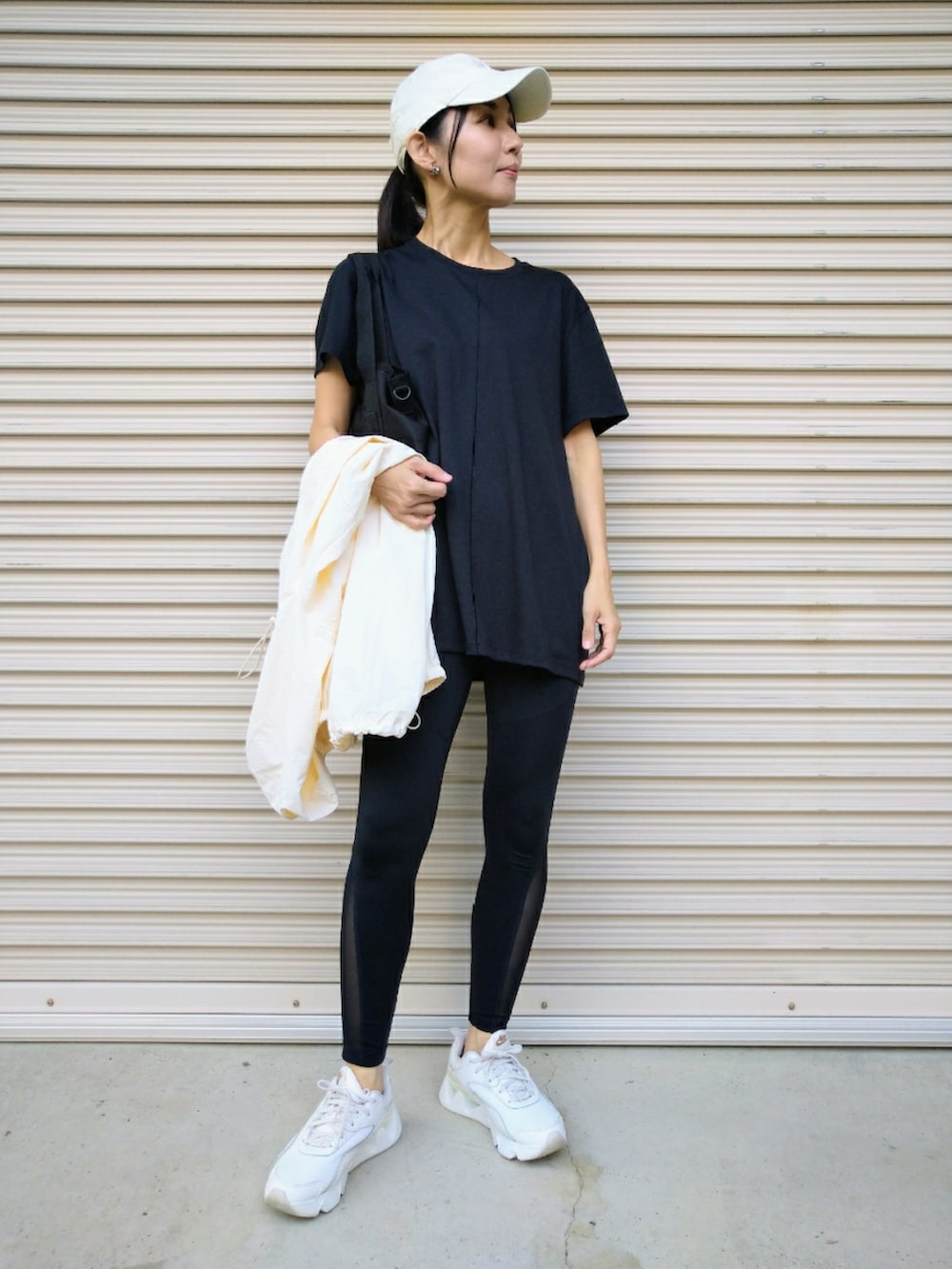 ホワイト系のスニーカー、ブラック系のトートバッグ、ブラック系のレギンス/スパッツを着用したレディースの秋コーディネートの3枚目の写真