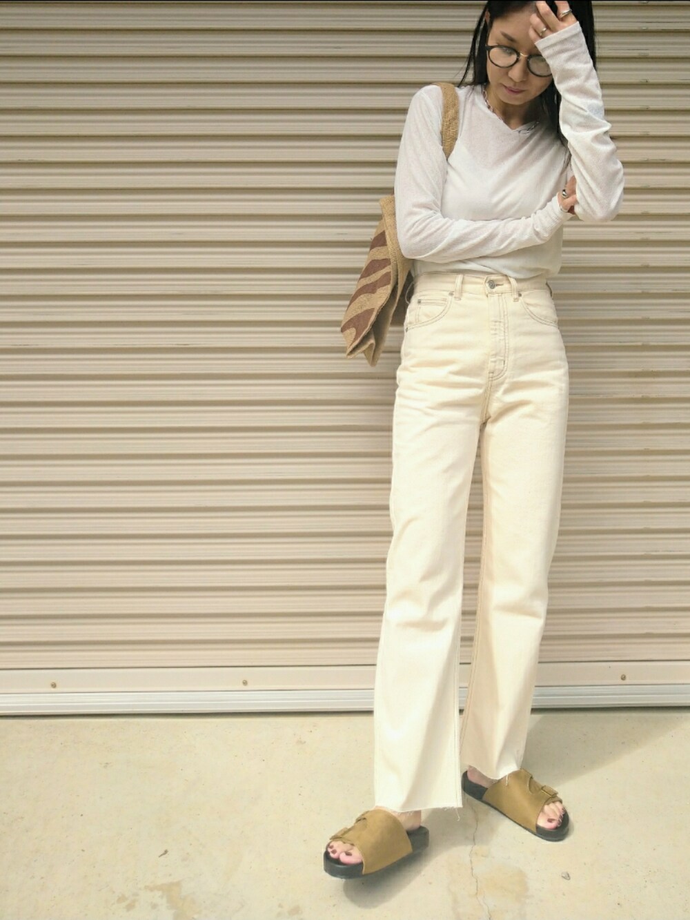 ブラック系のトップス、ホワイト系のデニムパンツ、ブラウン系のトートバッグを着用したレディースの秋コーディネートの3枚目の写真