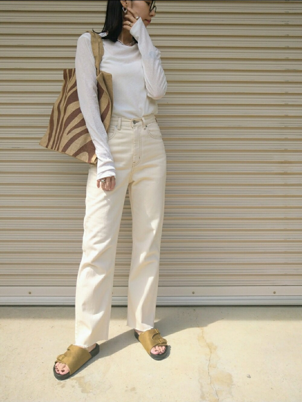 ブラック系のトップス、ホワイト系のデニムパンツ、ブラウン系のトートバッグを着用したレディースの秋コーディネートの2枚目の写真