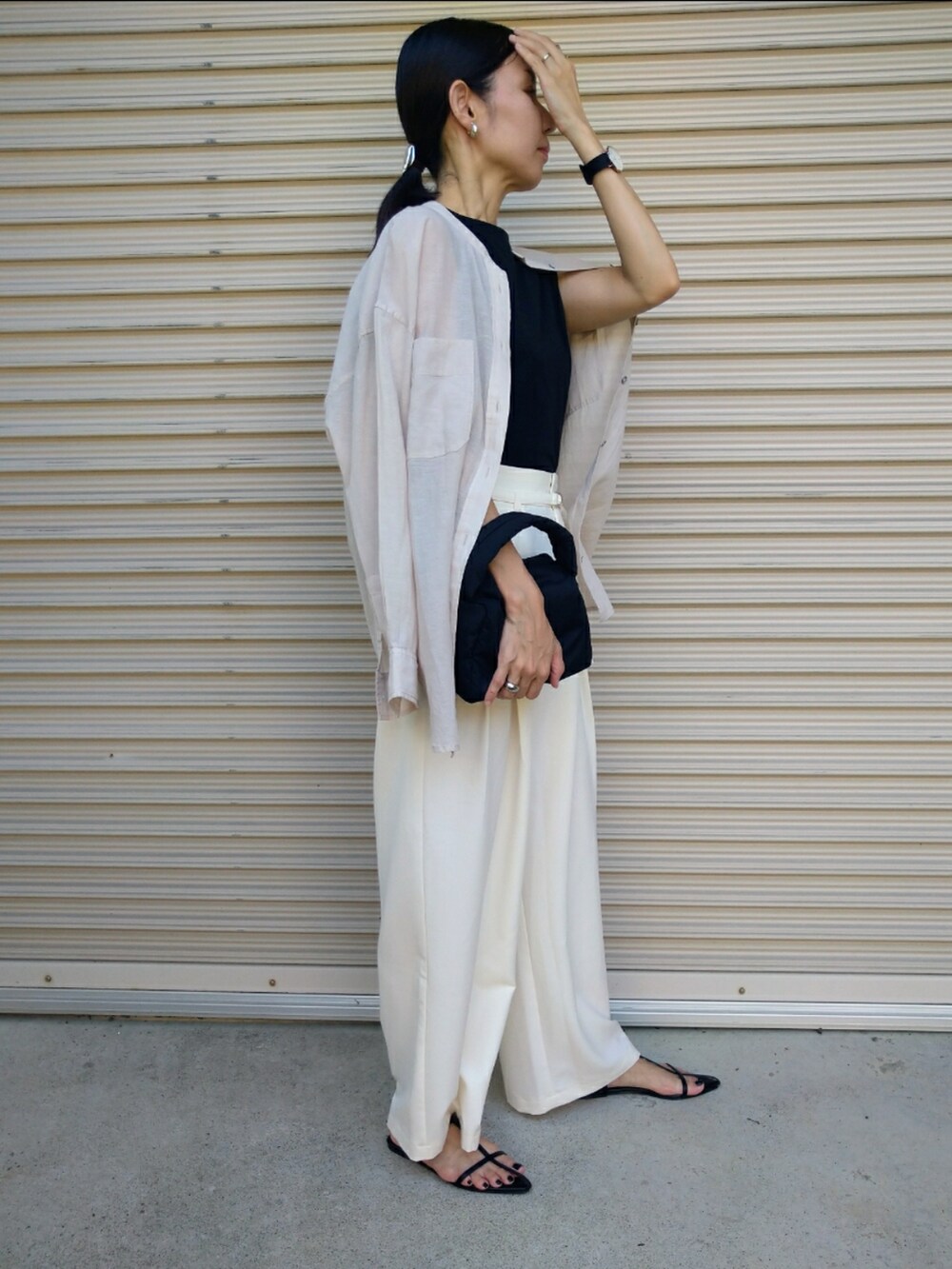 ホワイト系のシャツ/ブラウス、ホワイト系のスラックス、ブラック系のハンドバッグを着用したレディースの夏コーディネートの3枚目の写真