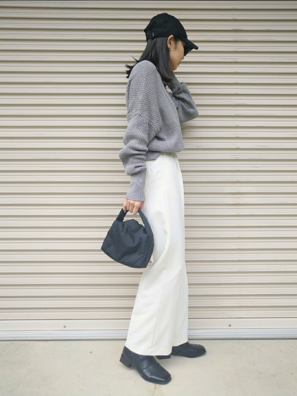 グレー系のニット/セーター、ホワイト系のその他パンツ、ブラック系のハンドバッグを着用したレディースの秋コーディネートの4枚目の写真