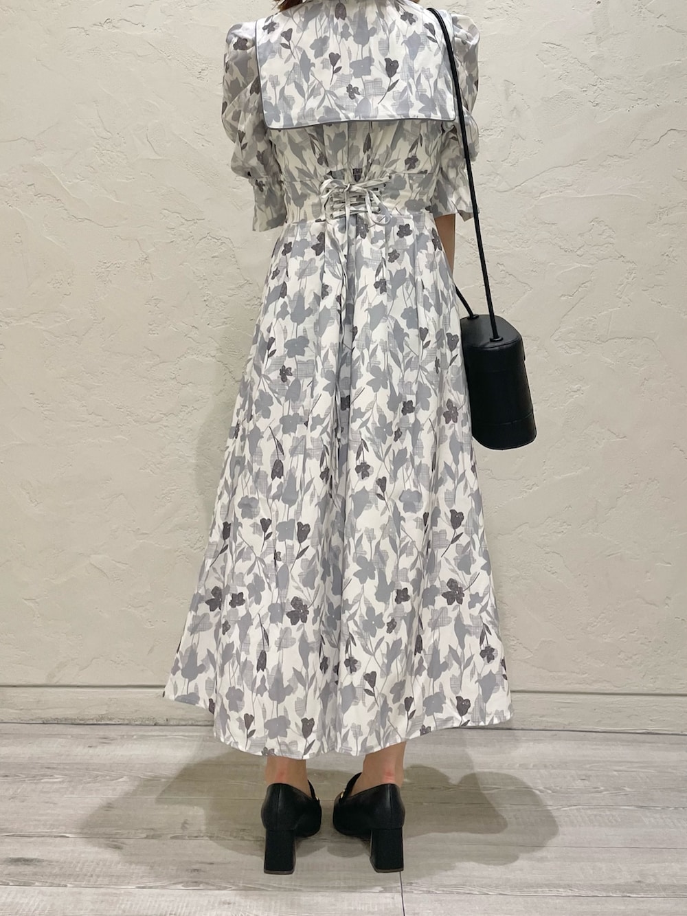 グレー系のワンピース、ブラック系のハンドバッグ、ブラック系のローファーを着用したレディースの秋コーディネートの3枚目の写真