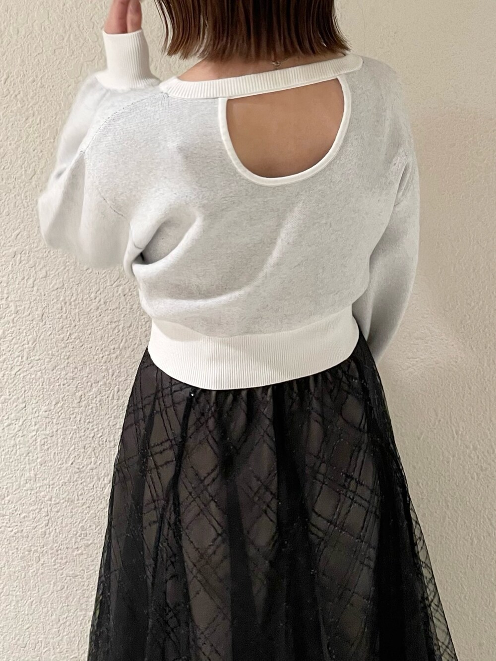 ブラック系のスカート、ホワイト系のニット/セーター、ブラック系のブーツを着用したレディースの冬コーディネートの6枚目の写真