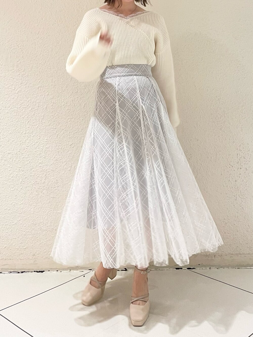 ホワイト系のニット/セーター、ホワイト系のパンプス、グレー系のスカートを着用したレディースの冬コーディネートの2枚目の写真