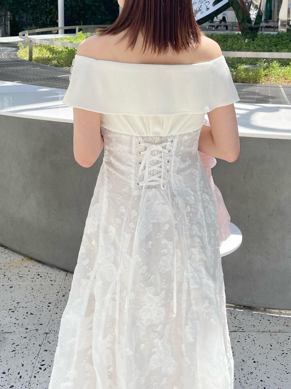 ホワイト系のワンピース、ピンク系のハンドバッグ、ホワイト系のパンプスを着用したレディースの春コーディネートの5枚目の写真