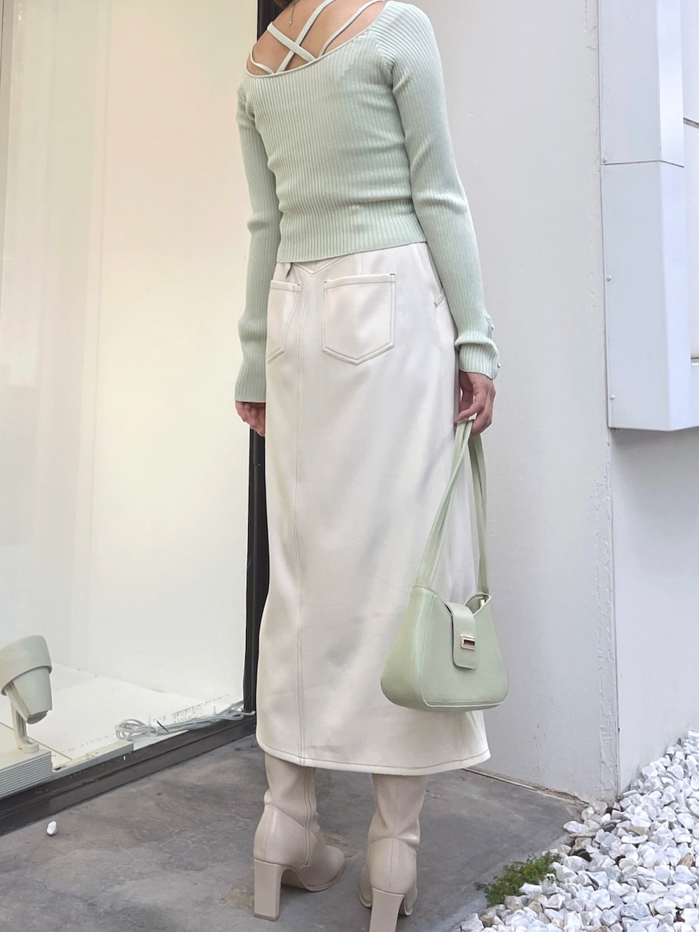 ホワイト系のブーツ、ホワイト系のスカート、グリーン系のニット/セーターを着用したレディースの秋コーディネートの2枚目の写真