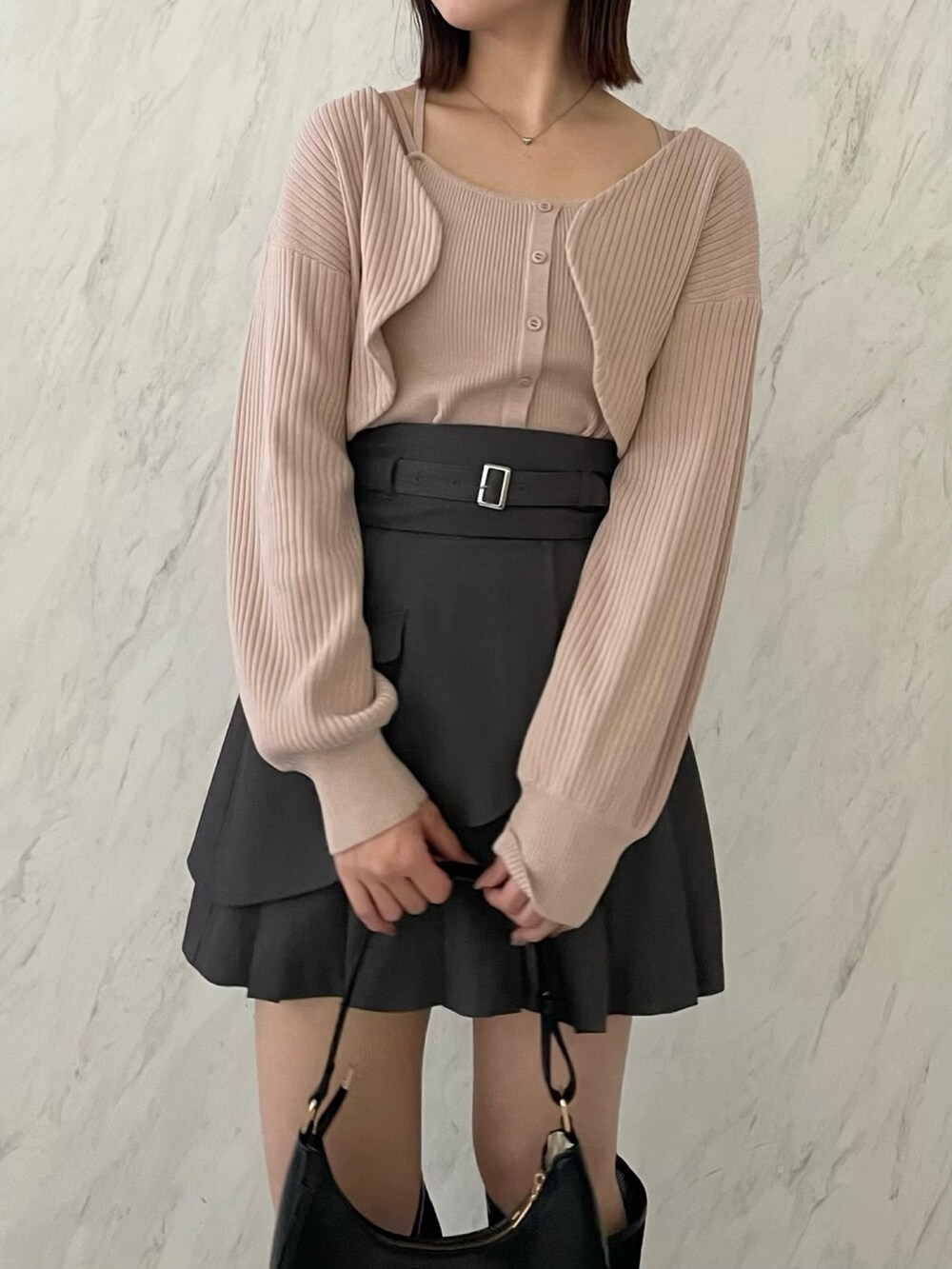 ピンク系のアンサンブル、グレー系のスカート、ブラック系のブーツを着用したレディースの冬コーディネートの3枚目の写真