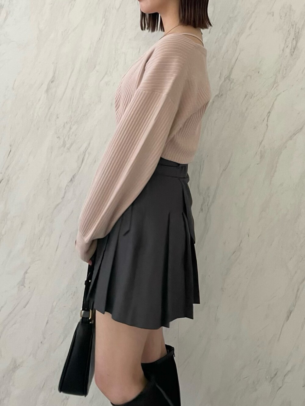 ピンク系のアンサンブル、グレー系のスカート、ブラック系のブーツを着用したレディースの冬コーディネートの4枚目の写真