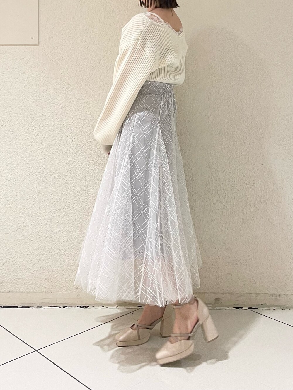 ホワイト系のニット/セーター、ホワイト系のパンプス、グレー系のスカートを着用したレディースの冬コーディネートの3枚目の写真