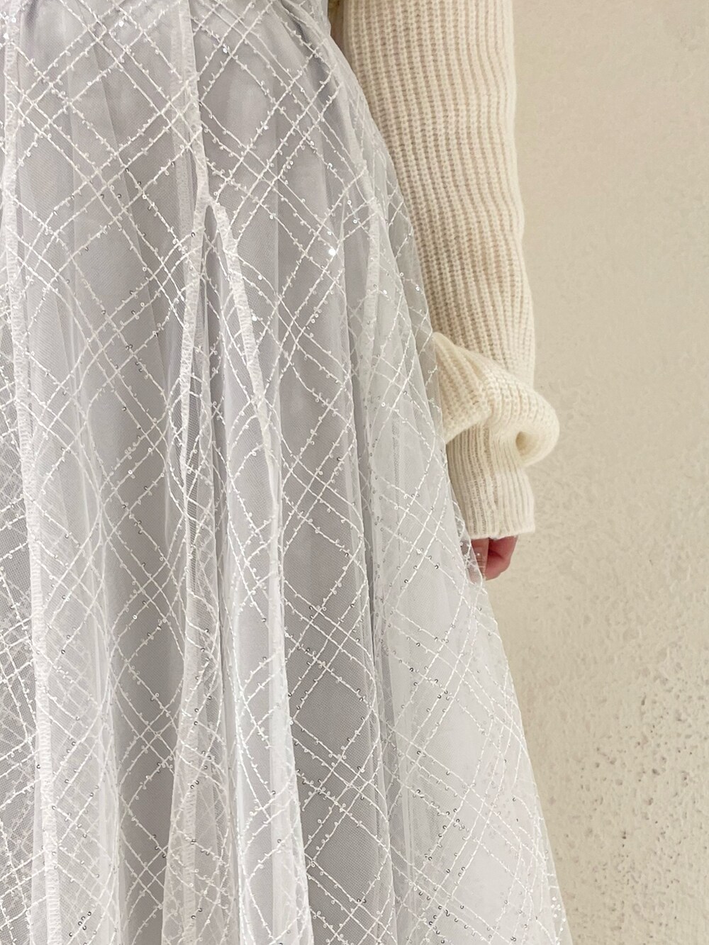 ホワイト系のニット/セーター、ホワイト系のパンプス、グレー系のスカートを着用したレディースの冬コーディネートの5枚目の写真