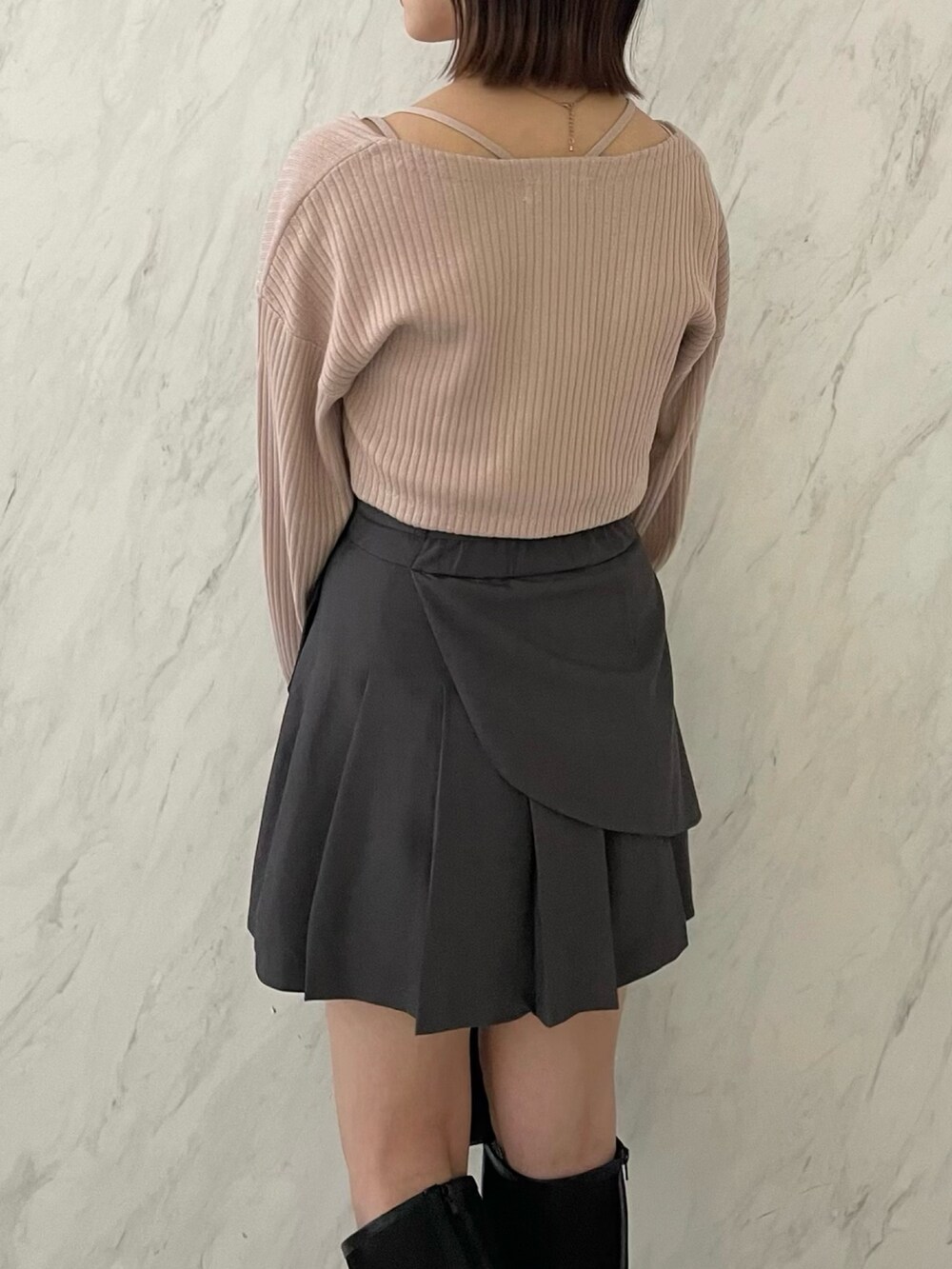 ピンク系のアンサンブル、グレー系のスカート、ブラック系のブーツを着用したレディースの冬コーディネートの5枚目の写真