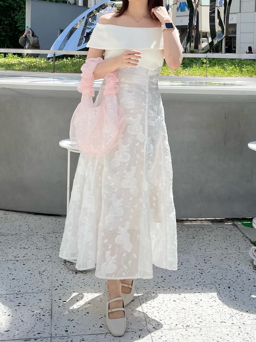 ホワイト系のワンピース、ピンク系のハンドバッグ、ホワイト系のパンプスを着用したレディースの春コーディネートの2枚目の写真