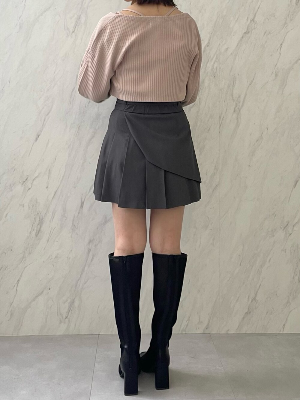 ピンク系のアンサンブル、グレー系のスカート、ブラック系のブーツを着用したレディースの冬コーディネートの2枚目の写真