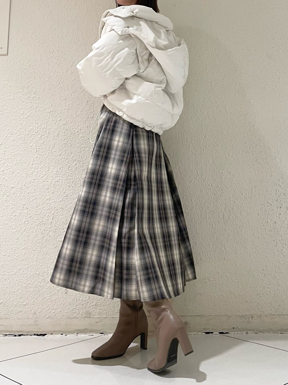 ホワイト系のニット/セーター、ホワイト系のダウンジャケット/コート、ブラウン系のスカートを着用したレディースの冬コーディネートの2枚目の写真