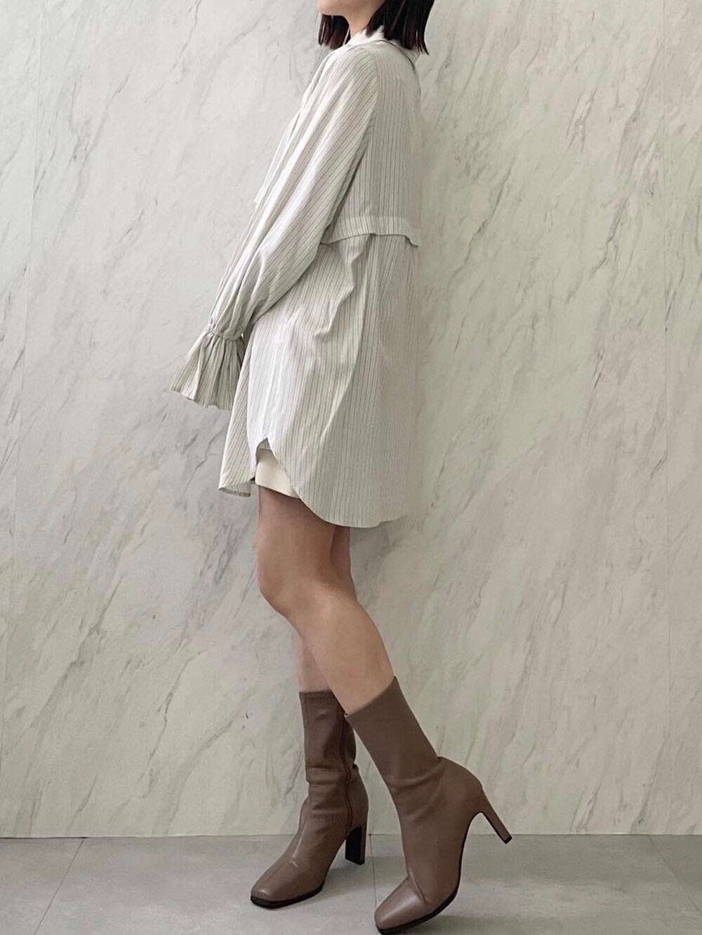 イエロー系のワンピース、ベージュ系のブーツを着用したレディースの冬コーディネートの2枚目の写真