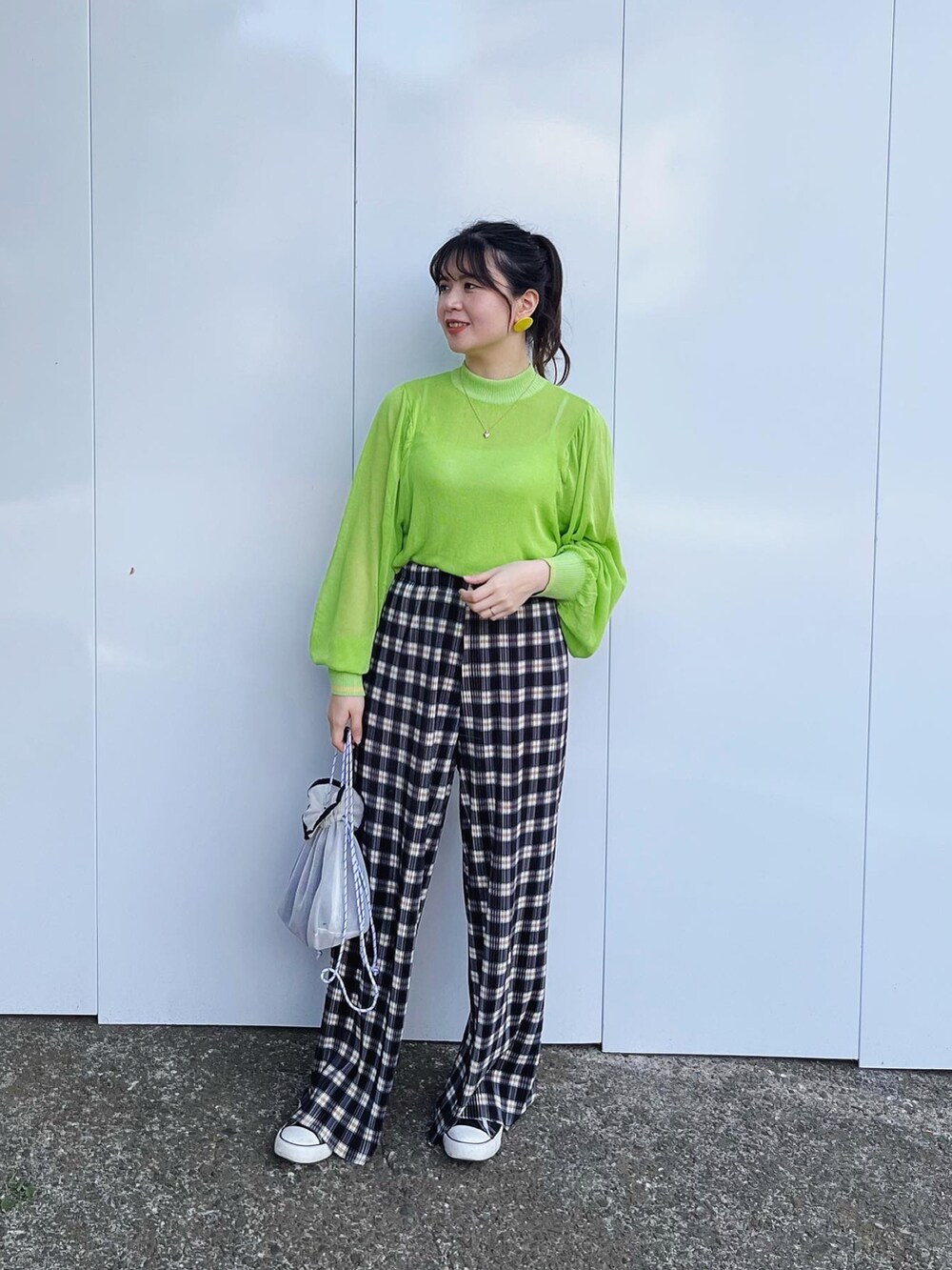 ホワイト系のクラッチバッグ、ブルー系のチノパンツ、グリーン系のニット/セーターを着用したレディースの春コーディネートの2枚目の写真