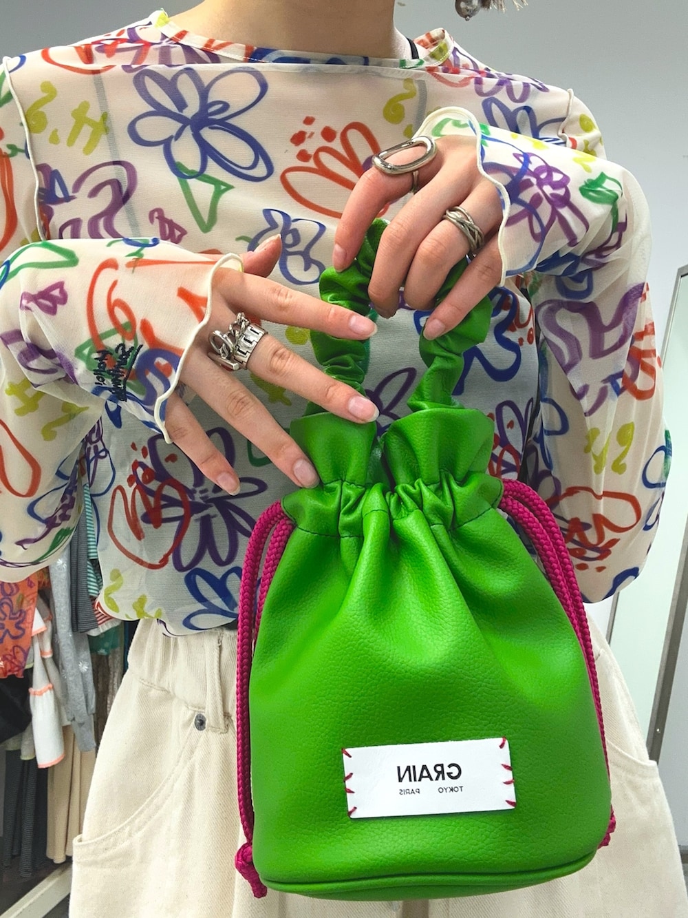 ホワイト系のTシャツ/カットソー、グリーン系のハンドバッグ、ホワイト系のデニムパンツを着用したレディースの冬コーディネートの3枚目の写真