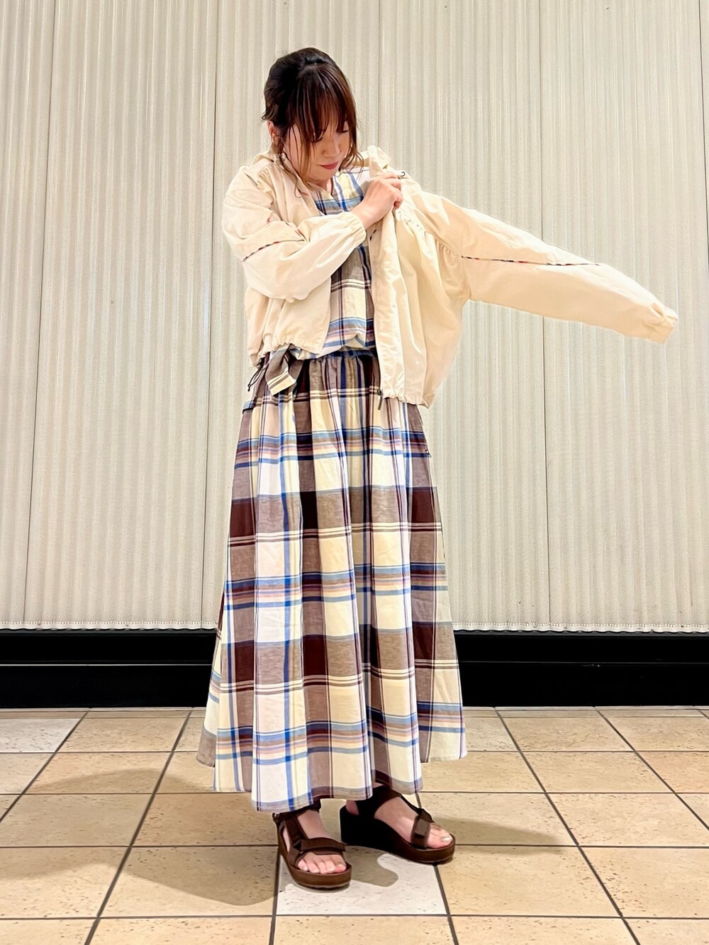 ベージュ系のショルダーバッグ、ブラウン系のサンダル、ホワイト系のナイロンジャケットを着用したレディースの春コーディネートの4枚目の写真