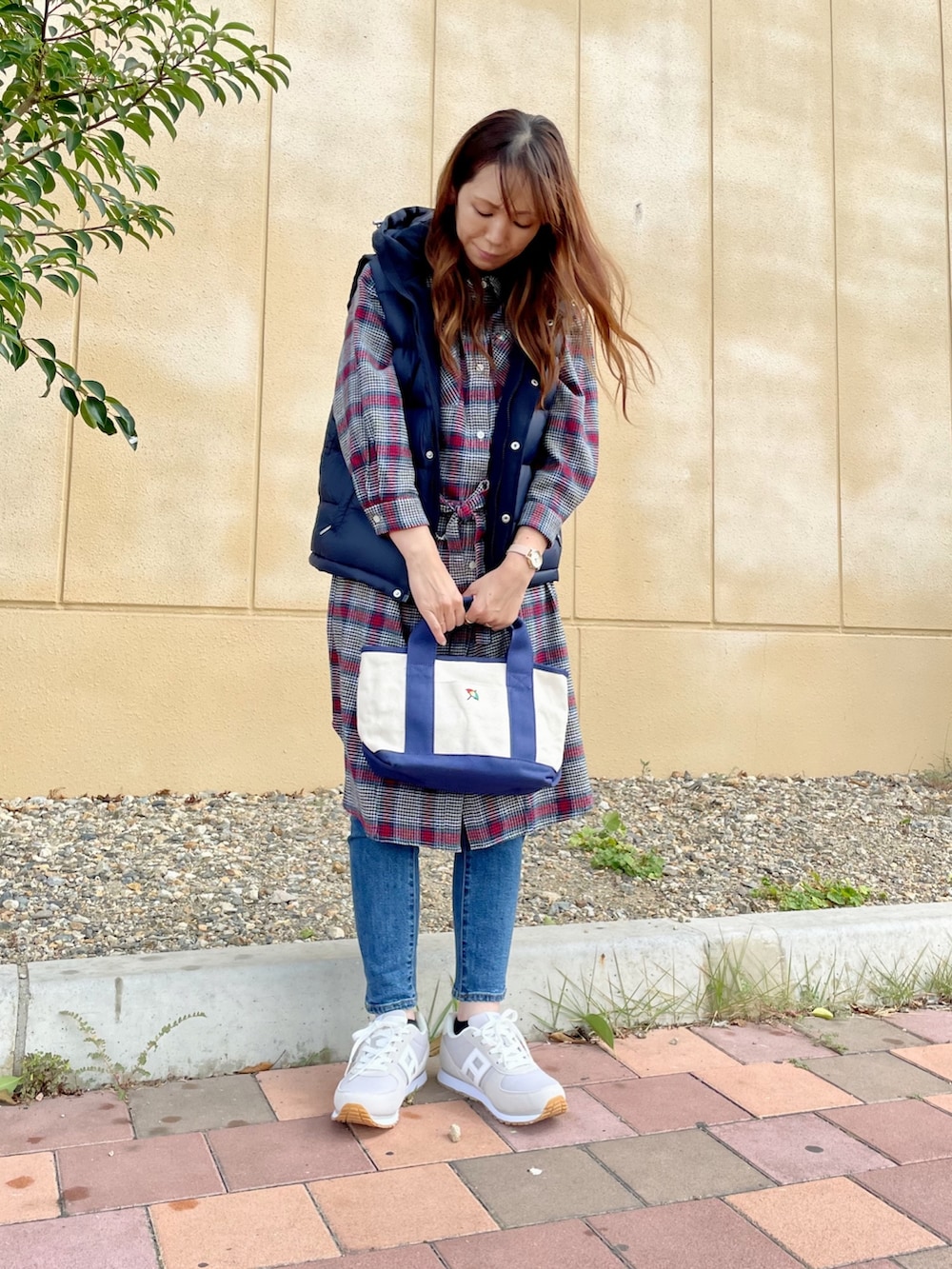 ブルー系のダウンベスト、ブルー系のデニムパンツ、ブルー系のトートバッグを着用したレディースの秋コーディネートの2枚目の写真