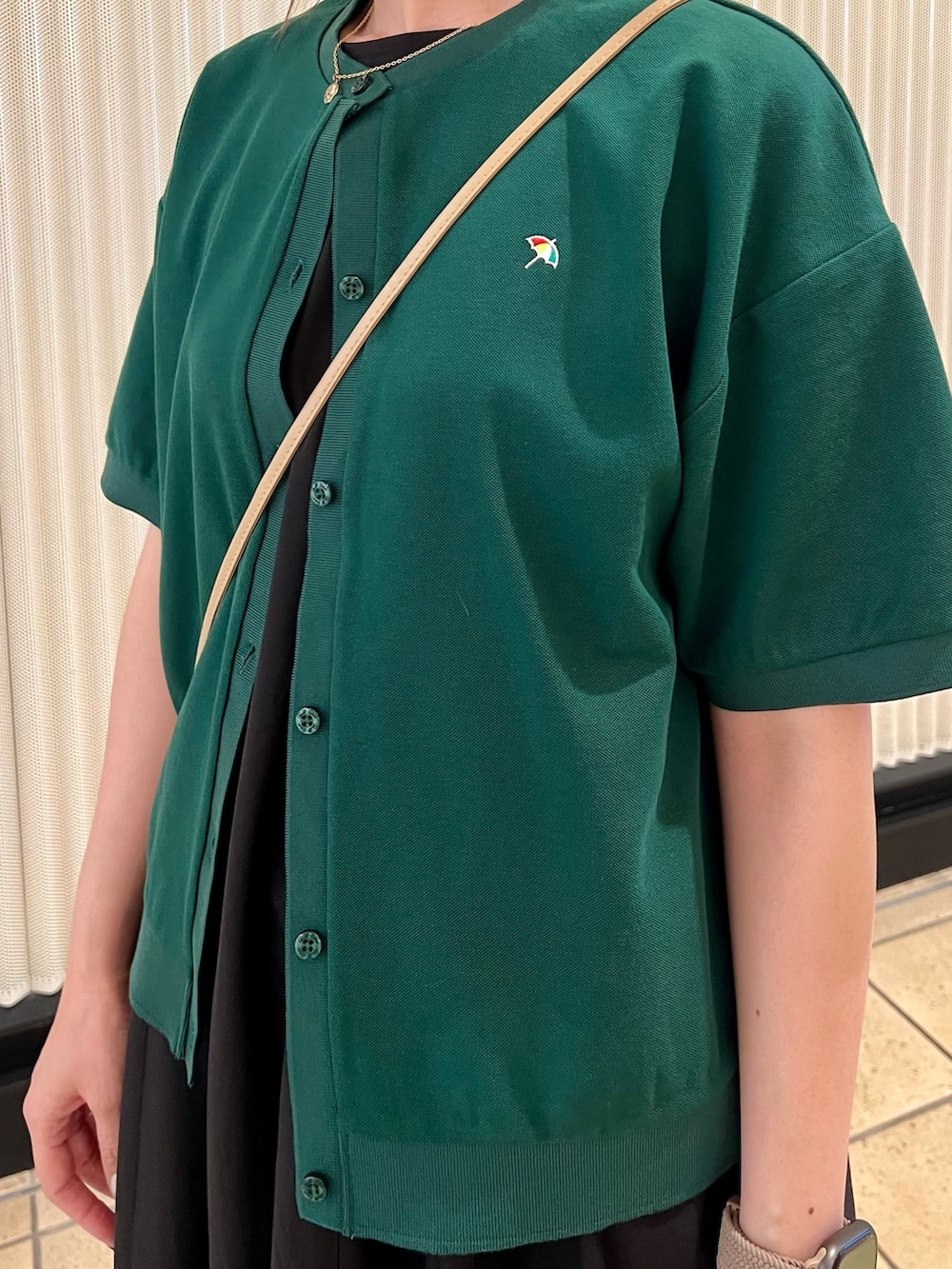 ブラック系のワンピース、ベージュ系のショルダーバッグ、グリーン系のカーディガン/ボレロを着用したレディースの春コーディネートの8枚目の写真