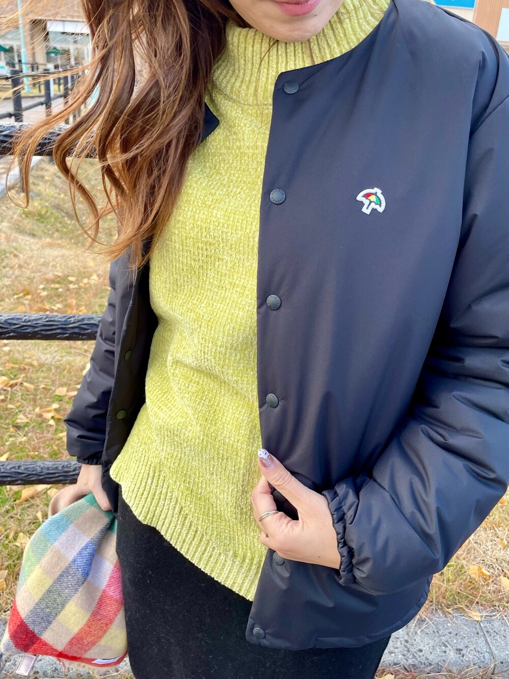 ブラック系のその他アウター、イエロー系のニット/セーター、ブラック系のスカートを着用したレディースの冬コーディネートの6枚目の写真