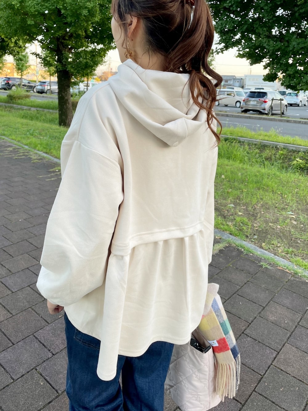 グレー系のスニーカー、ホワイト系のトートバッグ、ブルー系のデニムパンツを着用したレディースの秋コーディネートの4枚目の写真