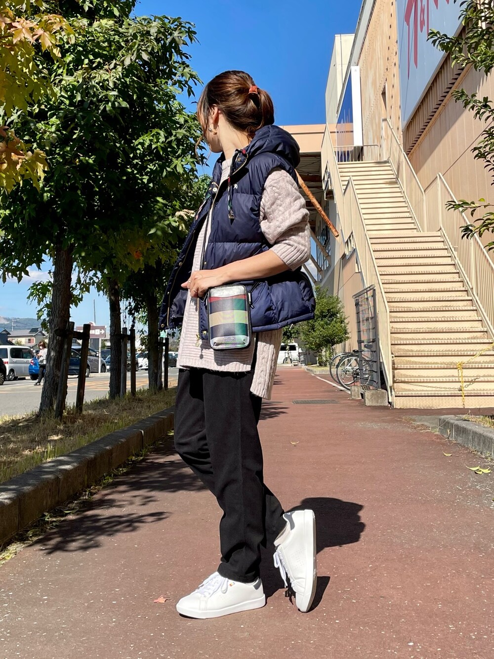 ピンク系のニット/セーター、ブルー系のダウンベスト、ブラック系のショルダーバッグを着用したレディースの秋コーディネートの3枚目の写真