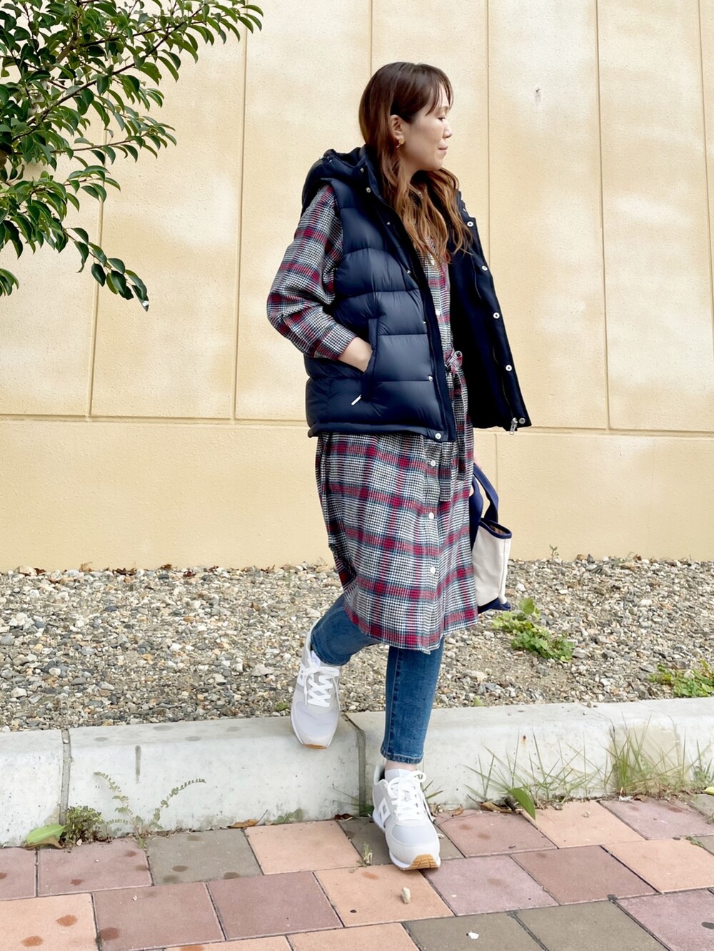 ブルー系のダウンベスト、ブルー系のデニムパンツ、ブルー系のトートバッグを着用したレディースの秋コーディネートの3枚目の写真