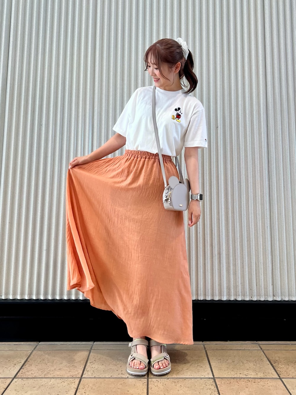 オレンジ系のスカート、ベージュ系のサンダル、ホワイト系のTシャツ/カットソーを着用したレディースの夏コーディネートの2枚目の写真