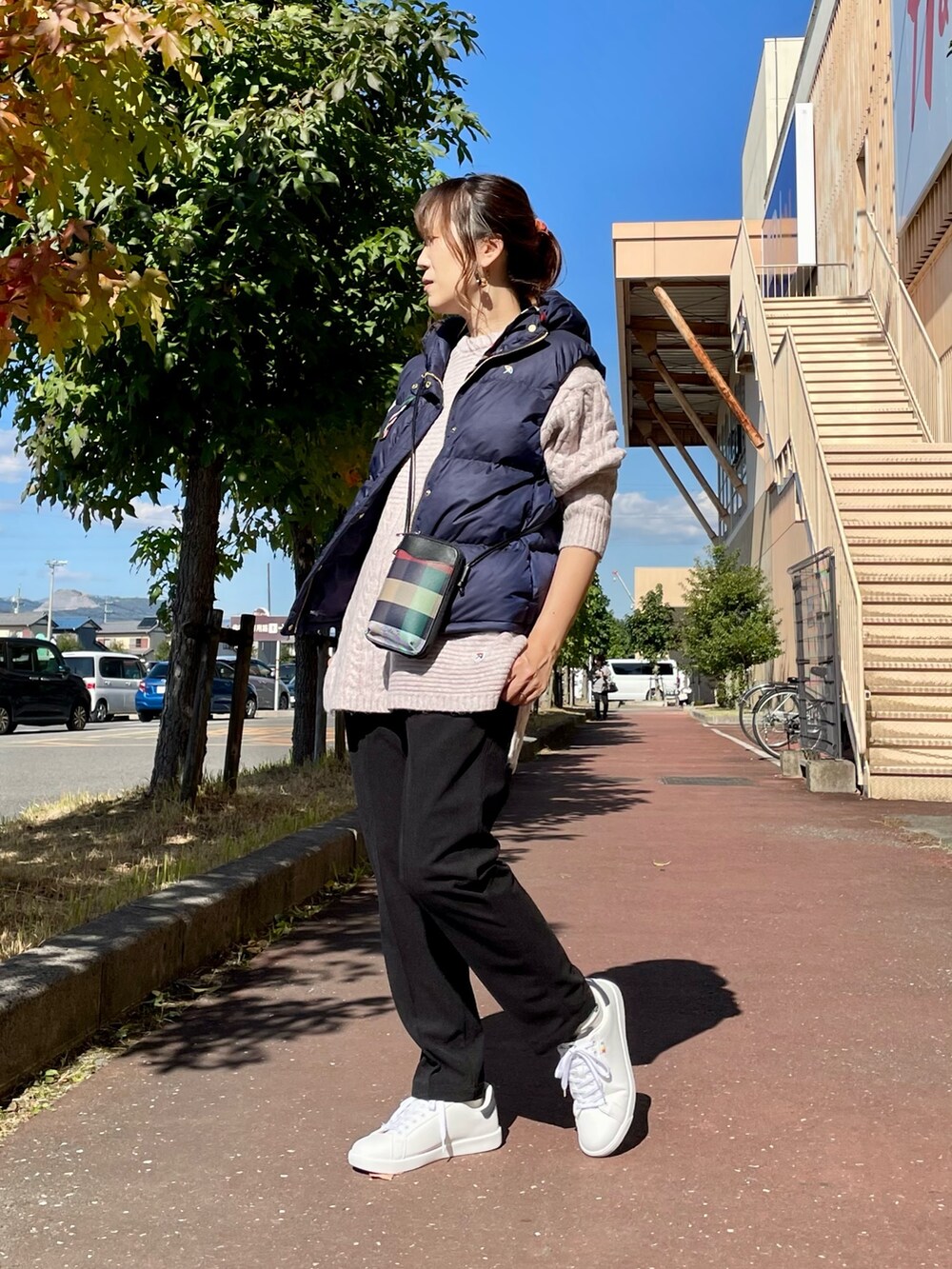 ピンク系のニット/セーター、ブルー系のダウンベスト、ブラック系のショルダーバッグを着用したレディースの秋コーディネートの4枚目の写真