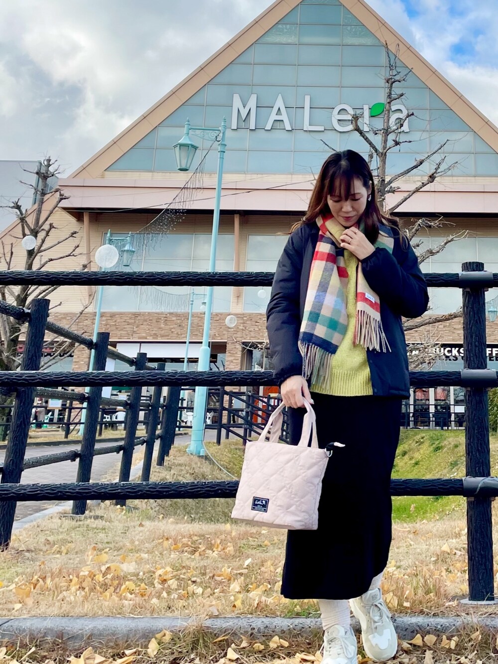 ブラック系のその他アウター、イエロー系のニット/セーター、ブラック系のスカートを着用したレディースの冬コーディネートの2枚目の写真