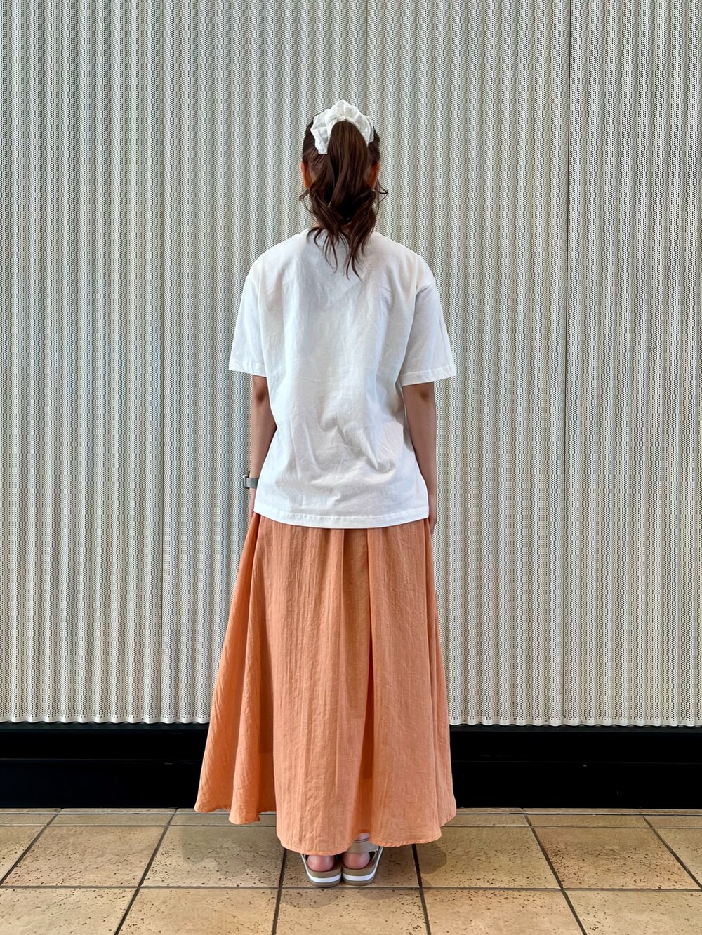 オレンジ系のスカート、ベージュ系のサンダル、ホワイト系のTシャツ/カットソーを着用したレディースの夏コーディネートの10枚目の写真