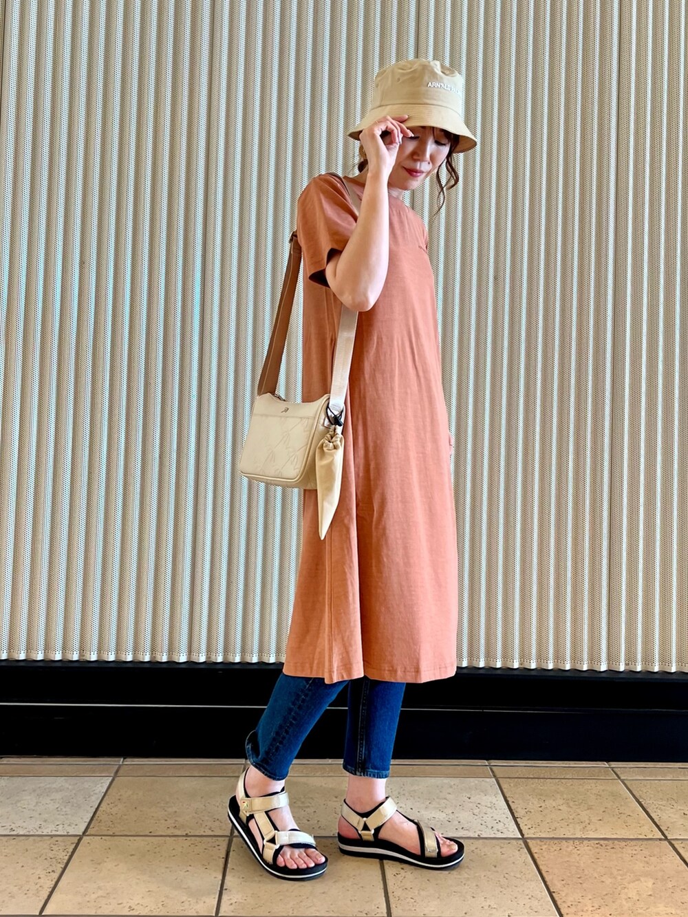 ブラウン系のワンピース、ホワイト系のショルダーバッグ、ブルー系のデニムパンツを着用したレディースの夏コーディネートの5枚目の写真