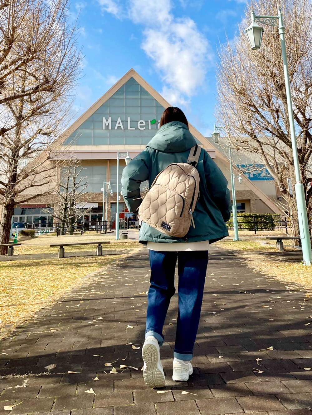 グリーン系のダウンジャケット/コート、ホワイト系のチュニック、ブルー系のデニムパンツを着用したレディースの冬コーディネートの4枚目の写真