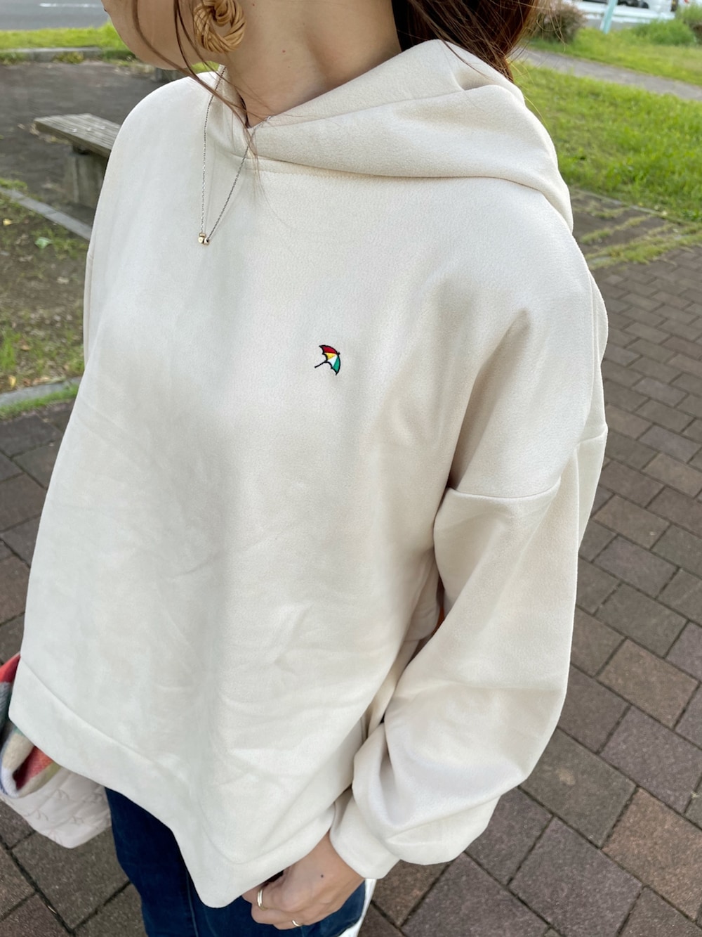 グレー系のスニーカー、ホワイト系のトートバッグ、ブルー系のデニムパンツを着用したレディースの秋コーディネートの5枚目の写真