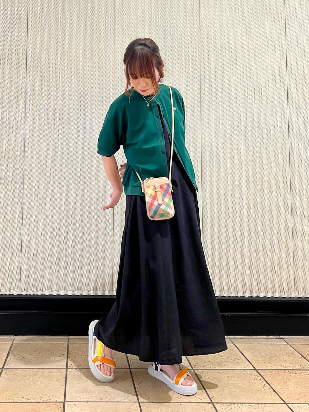 ブラック系のワンピース、ベージュ系のショルダーバッグ、グリーン系のカーディガン/ボレロを着用したレディースの春コーディネートの7枚目の写真