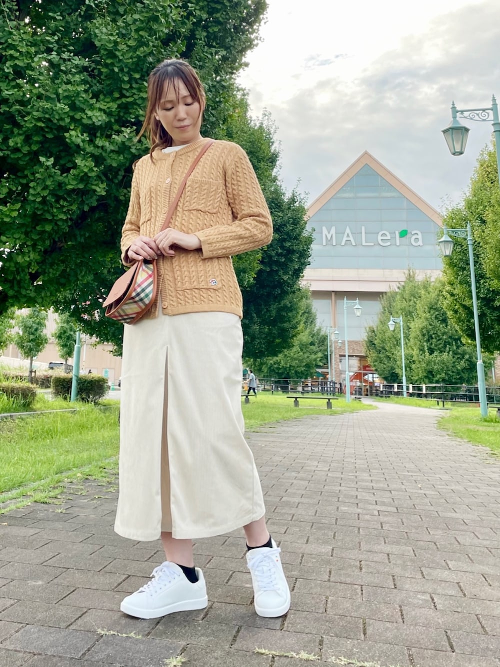 ブラウン系のショルダーバッグ、イエロー系のカーディガン/ボレロ、ホワイト系のスニーカーを着用したレディースの秋コーディネートの2枚目の写真