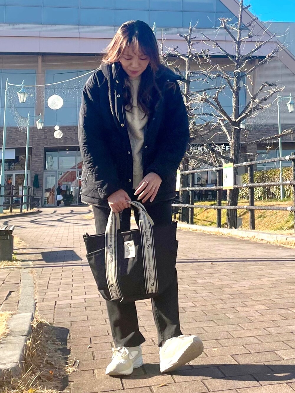 ブラック系のその他アウター、ホワイト系のTシャツ/カットソー、ブラック系のトートバッグを着用したレディースの冬コーディネートの2枚目の写真