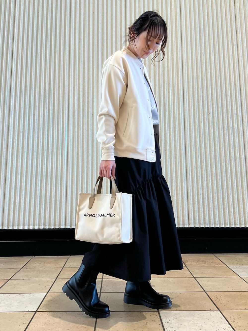 ホワイト系のブルゾン、グレー系のニット/セーター、ブラック系のスカートを着用したレディースの春コーディネートの3枚目の写真