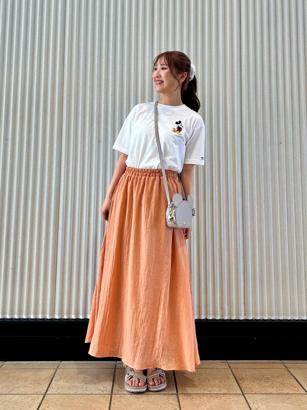 オレンジ系のスカート、ベージュ系のサンダル、ホワイト系のTシャツ/カットソーを着用したレディースの夏コーディネートの3枚目の写真