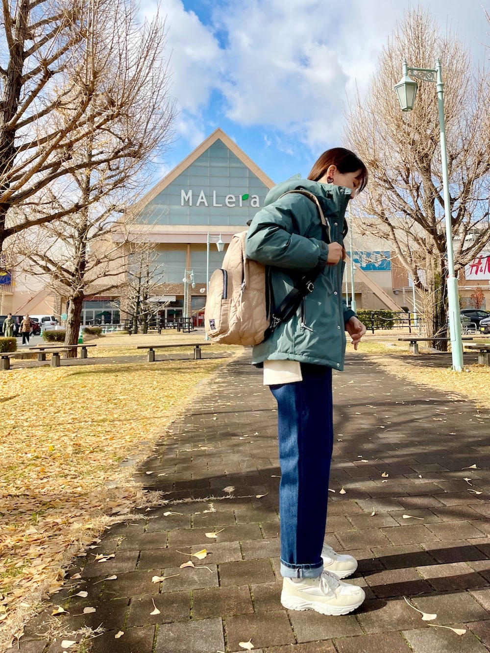 グリーン系のダウンジャケット/コート、ホワイト系のチュニック、ブルー系のデニムパンツを着用したレディースの冬コーディネートの3枚目の写真