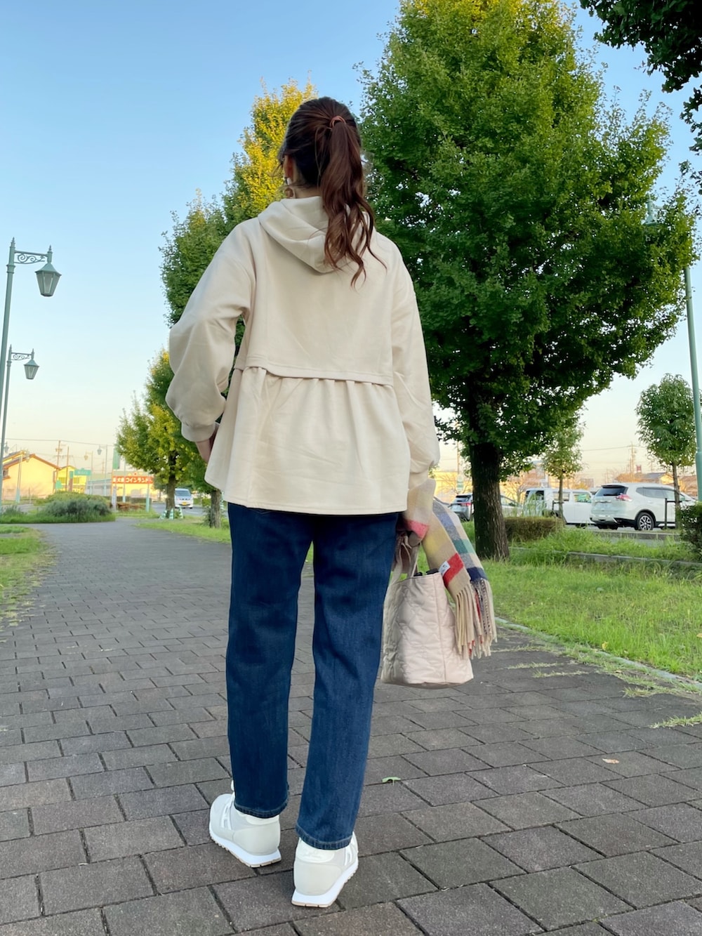 グレー系のスニーカー、ホワイト系のトートバッグ、ブルー系のデニムパンツを着用したレディースの秋コーディネートの3枚目の写真