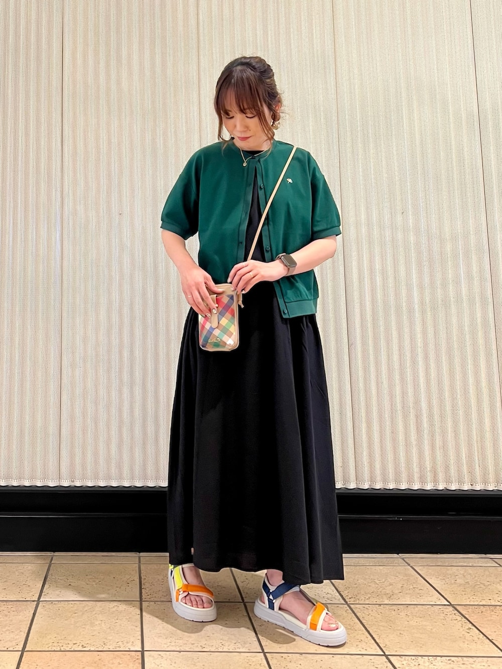 ブラック系のワンピース、ベージュ系のショルダーバッグ、グリーン系のカーディガン/ボレロを着用したレディースの春コーディネートの5枚目の写真