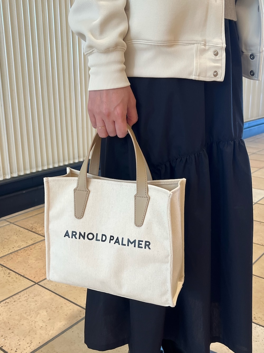 ホワイト系のブルゾン、グレー系のニット/セーター、ブラック系のスカートを着用したレディースの春コーディネートの6枚目の写真