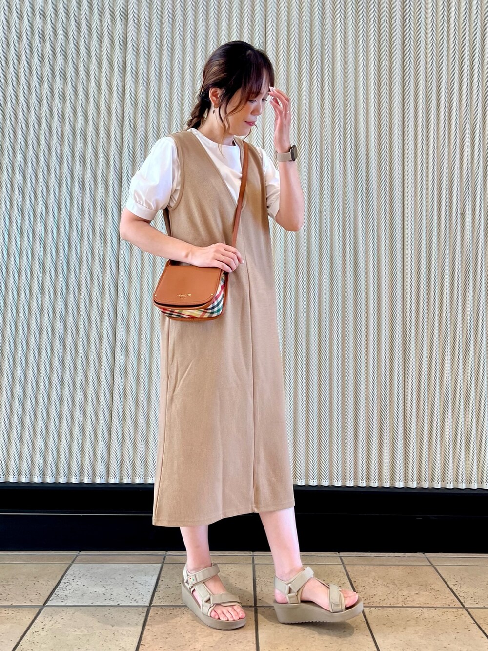 ブラウン系のショルダーバッグ、ベージュ系のジャンパースカート、ホワイト系のTシャツ/カットソーを着用したレディースの夏コーディネートの5枚目の写真