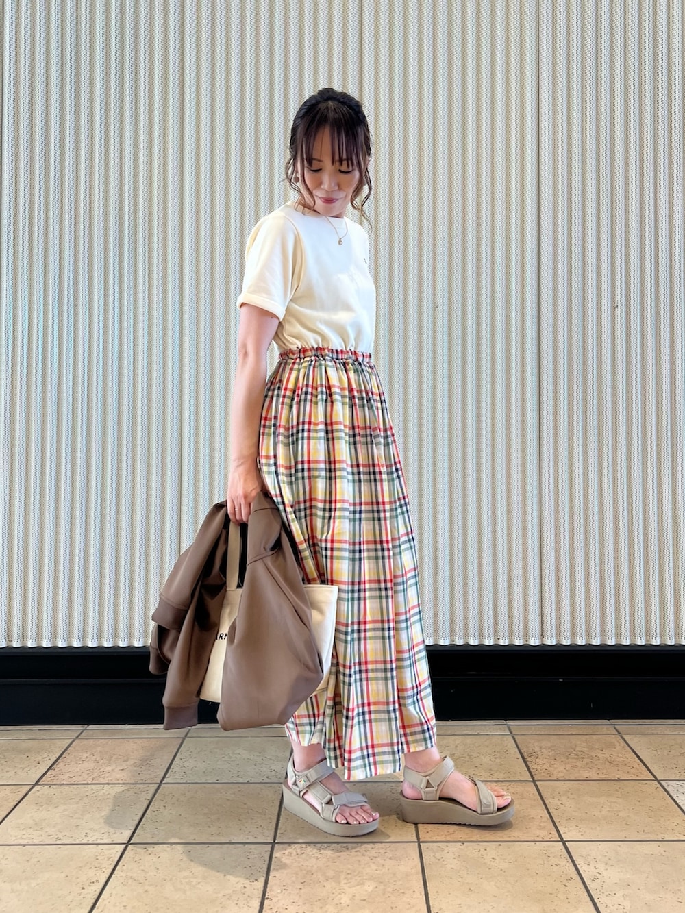 ホワイト系のトートバッグ、ベージュ系のサンダル、ブラウン系のパーカーを着用したレディースの春コーディネートの4枚目の写真